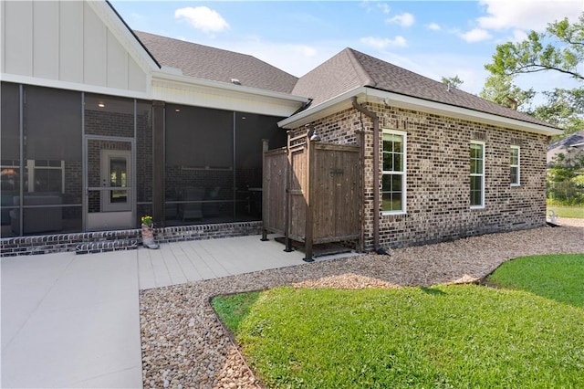 98 Bartram Trl, Brunswick, GA 31523 - view of side of property with brick siding, a sunroom, a patio, and a shingled roof