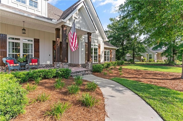 98 Bartram Trl, Brunswick, GA 31523 - entrance to property featuring a porch, roof with shingles, board and batten siding, and a yard