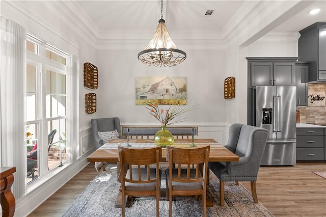 98 Bartram Trl, Brunswick, GA 31523 - dining space with a chandelier, light wood finished floors, ornamental molding, and a wainscoted wall