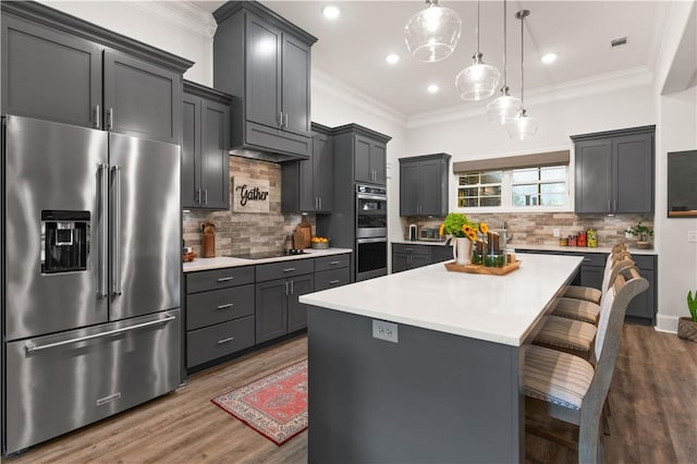 98 Bartram Trl, Brunswick, GA 31523 - kitchen with appliances with stainless steel finishes, light countertops, a center island, ornamental molding, and a kitchen bar