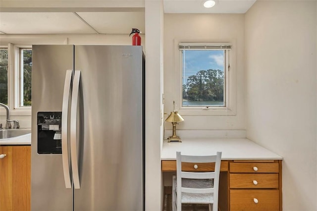 kitchen with brown cabinetry, plenty of natural light, stainless steel refrigerator with ice dispenser, and a sink