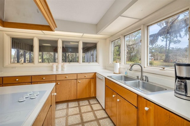 kitchen featuring white appliances, brown cabinetry, light countertops, light floors, and a sink