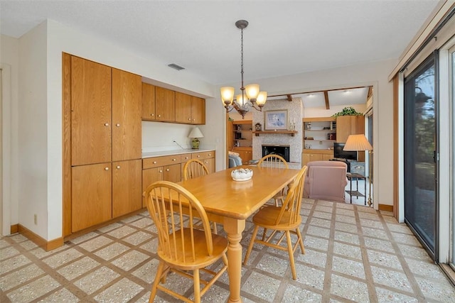 dining space with a chandelier, a brick fireplace, visible vents, and baseboards