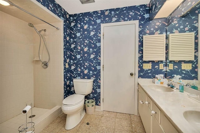 full bath featuring a stall shower, a sink, toilet, and wallpapered walls