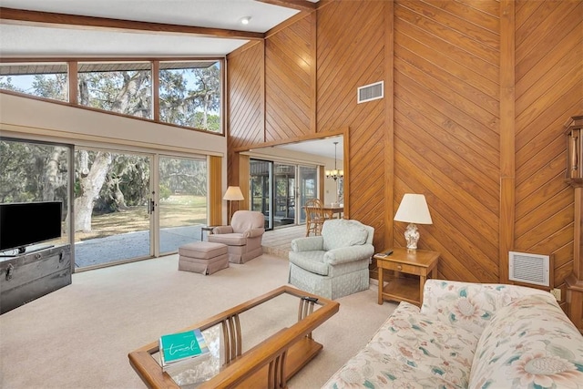 living room with light colored carpet, beam ceiling, visible vents, and wooden walls