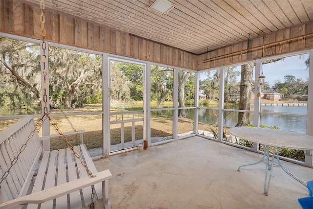 unfurnished sunroom with wood ceiling and a water view