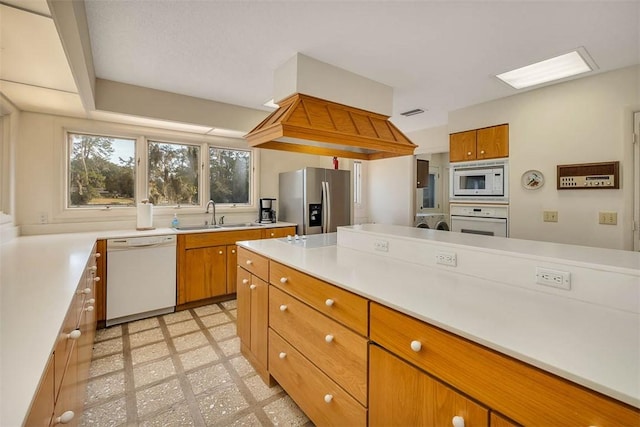 kitchen featuring brown cabinets, light floors, light countertops, a sink, and white appliances