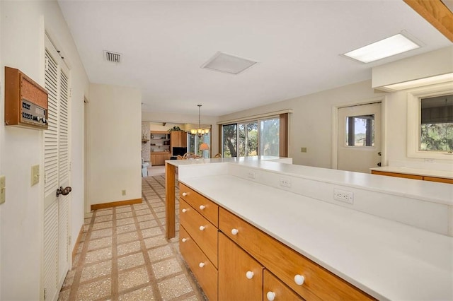 kitchen with light floors, light countertops, visible vents, and brown cabinets