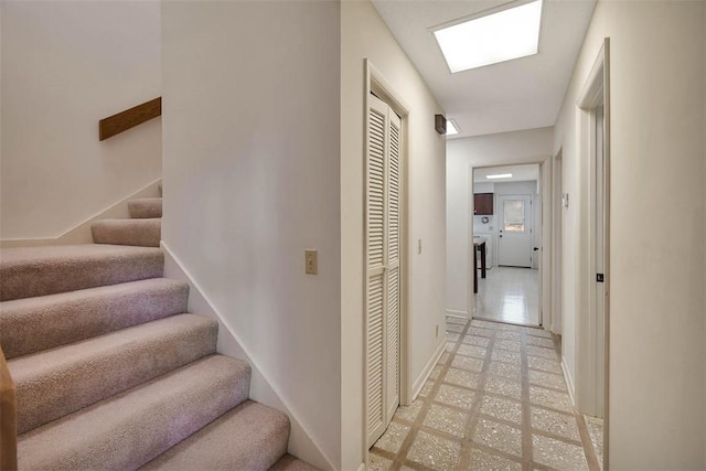 stairs with a skylight and baseboards