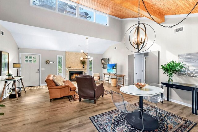 living room with wood-type flooring, a large fireplace, an inviting chandelier, and a wealth of natural light