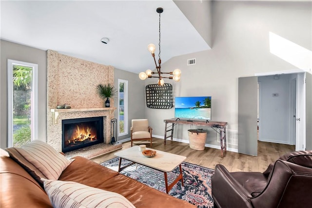 living room with a fireplace, light hardwood / wood-style flooring, a healthy amount of sunlight, and a notable chandelier