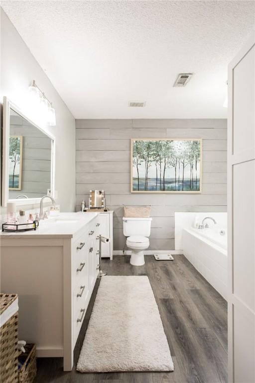 313 White Pine Highway, Nicholls, GA 31554 - full bathroom with vanity, wooden walls, wood finished floors, a garden tub, and a textured ceiling