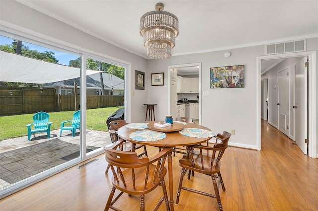 dining room featuring a notable chandelier, light hardwood / wood-style floors, and ornamental molding