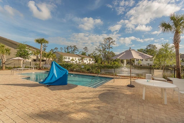 community pool featuring a residential view, fence, and a patio