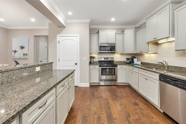 kitchen with dark hardwood / wood-style floors, crown molding, dark stone counters, appliances with stainless steel finishes, and sink