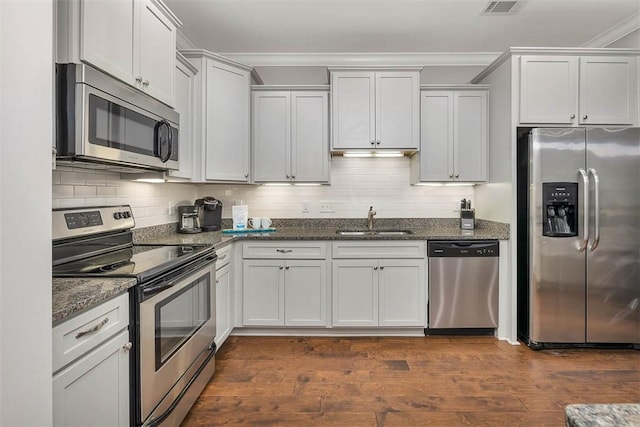 kitchen featuring dark wood finished floors, appliances with stainless steel finishes, backsplash, and a sink