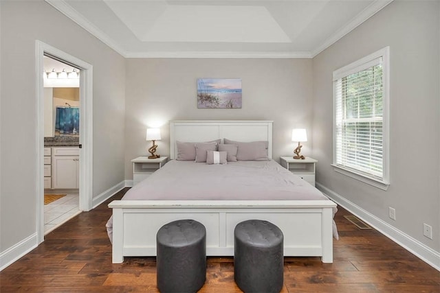 bedroom with crown molding, connected bathroom, a raised ceiling, and dark hardwood / wood-style floors