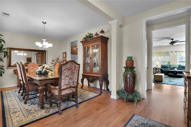 dining room featuring decorative columns, wood-type flooring, and ceiling fan with notable chandelier