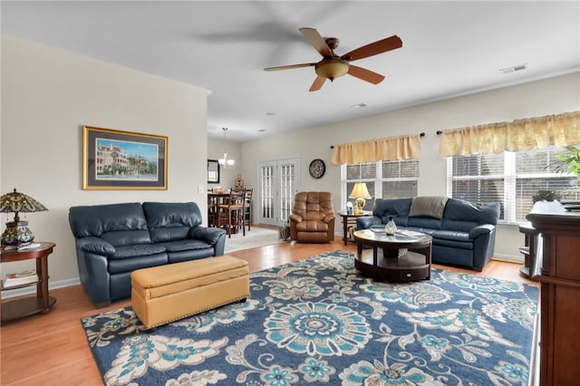 living room featuring plenty of natural light, ceiling fan with notable chandelier, and wood-type flooring