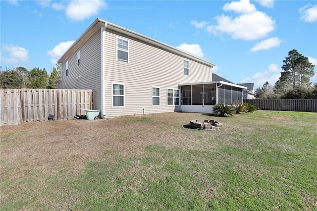 back of property featuring a sunroom, a fire pit, and a yard