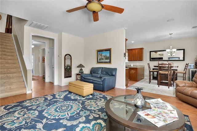 living room featuring ceiling fan with notable chandelier and light hardwood / wood-style floors