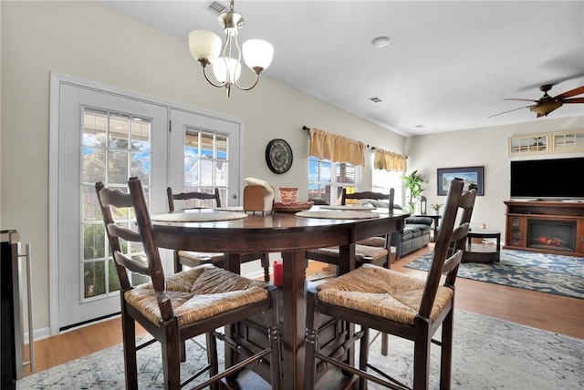 dining room with french doors, wood-type flooring, ceiling fan with notable chandelier, and plenty of natural light