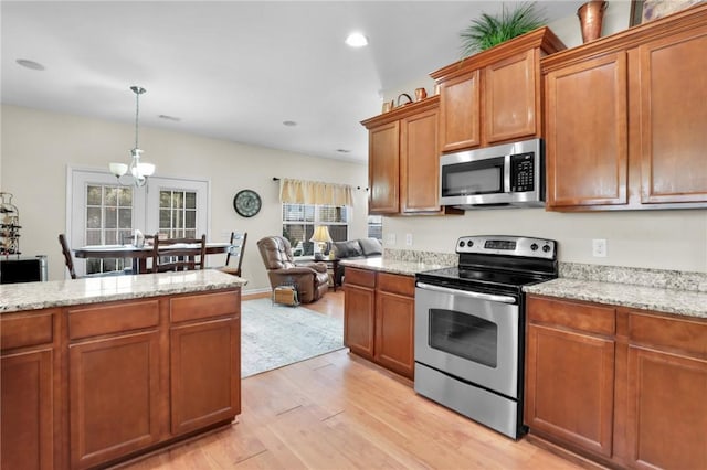 kitchen featuring plenty of natural light, pendant lighting, appliances with stainless steel finishes, and light hardwood / wood-style flooring