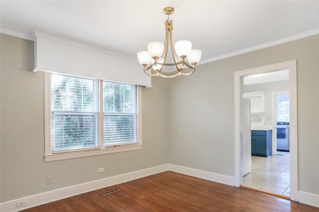 spare room with a notable chandelier, washer / dryer, ornamental molding, and light wood-type flooring