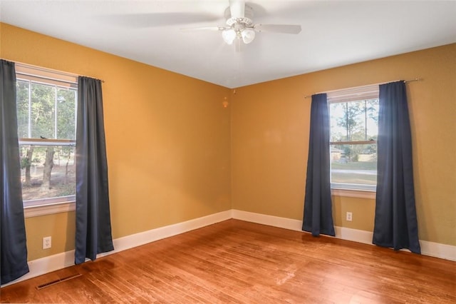 spare room featuring wood-type flooring, ceiling fan, and plenty of natural light