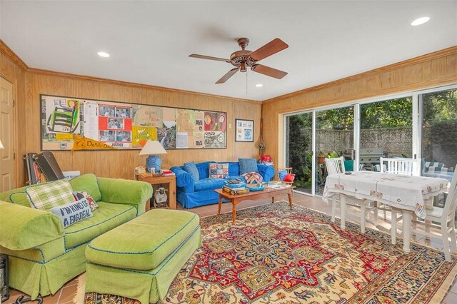 tiled living room featuring ceiling fan, ornamental molding, and wooden walls