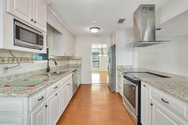 kitchen with appliances with stainless steel finishes, island range hood, sink, and white cabinets