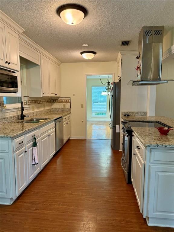 kitchen with white cabinetry, sink, wall chimney range hood, and stainless steel appliances