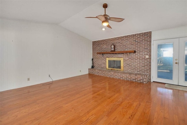 unfurnished living room with light hardwood / wood-style flooring, lofted ceiling, ceiling fan, a fireplace, and french doors