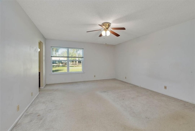 spare room featuring light colored carpet, ceiling fan, and a textured ceiling