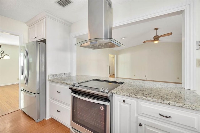 kitchen with appliances with stainless steel finishes, light hardwood / wood-style flooring, light stone counters, island exhaust hood, and white cabinetry