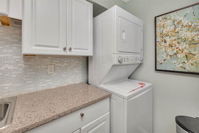 laundry room featuring stacked washer / dryer, sink, and cabinets