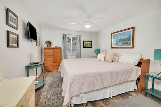 bedroom featuring ceiling fan, dark hardwood / wood-style floors, and a textured ceiling