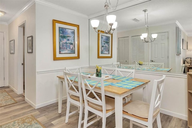 dining area with ornamental molding, light hardwood / wood-style floors, and a chandelier