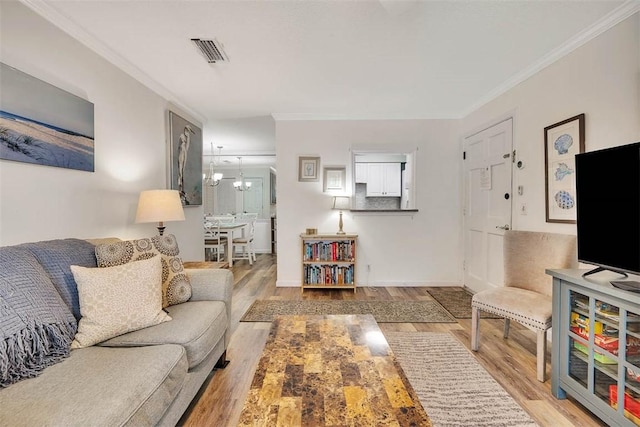 living room with crown molding, wood-type flooring, and a notable chandelier