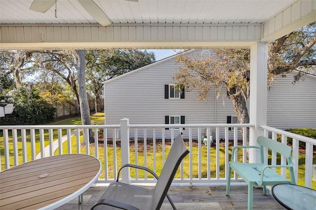 wooden terrace featuring ceiling fan and a lawn