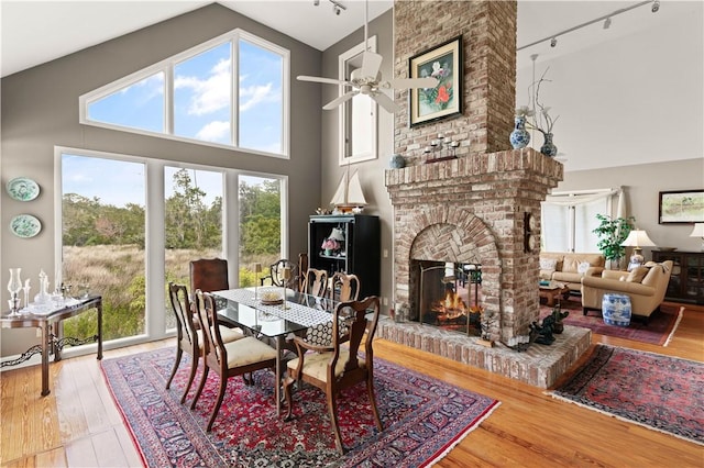 207 Military Rd, Saint Simons Island, GA 31522 - dining space featuring track lighting, high vaulted ceiling, ceiling fan, a fireplace, and wood finished floors