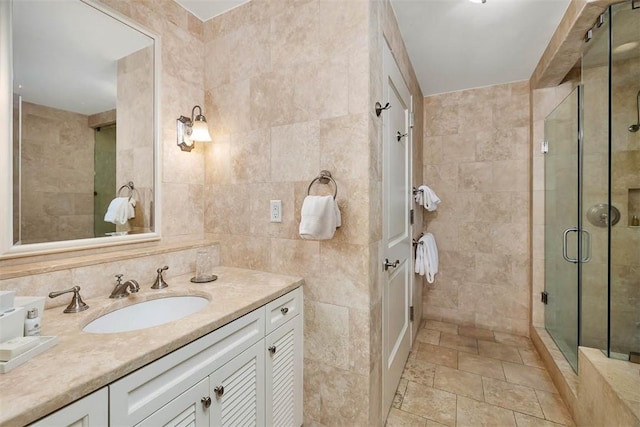 bathroom featuring walk in shower, vanity, and tile walls