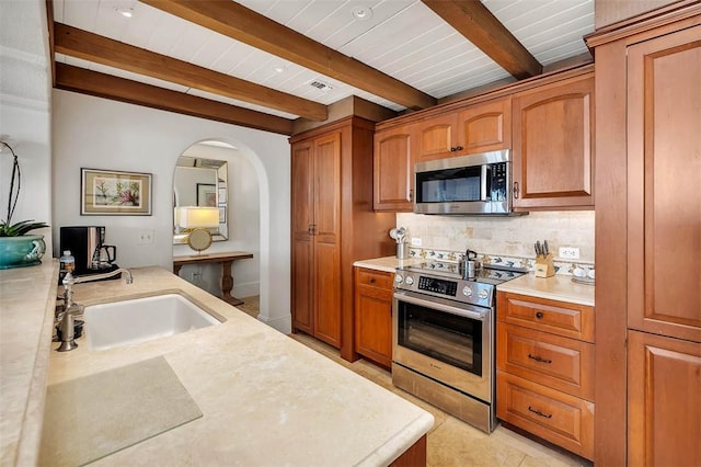 kitchen featuring beam ceiling, sink, light tile patterned floors, and stainless steel appliances