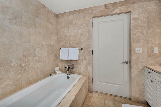 bathroom featuring tile patterned floors, vanity, tile walls, and tiled tub