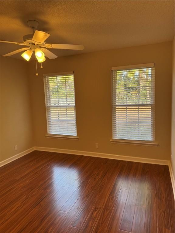 unfurnished room featuring ceiling fan, dark hardwood / wood-style flooring, a textured ceiling, and a wealth of natural light