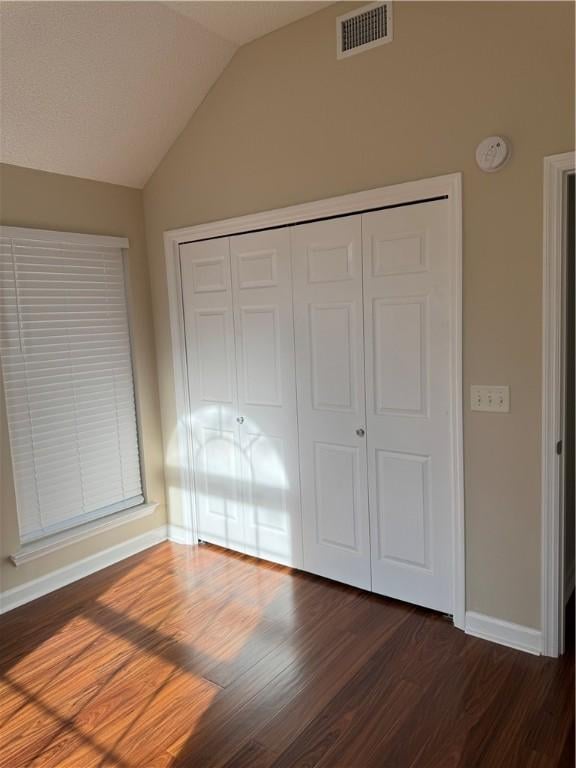 unfurnished bedroom with dark hardwood / wood-style flooring, a closet, and lofted ceiling