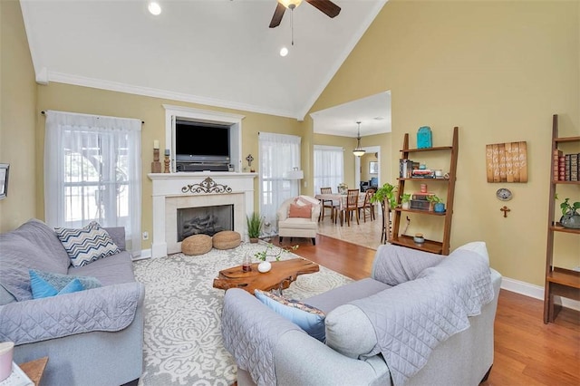 living room with a tiled fireplace, crown molding, plenty of natural light, and wood-type flooring