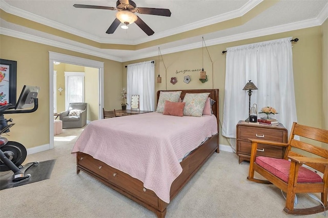 carpeted bedroom with a raised ceiling, ceiling fan, and ornamental molding