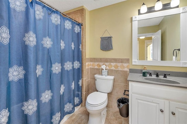 bathroom featuring a textured ceiling, vanity, tile walls, tile patterned flooring, and toilet