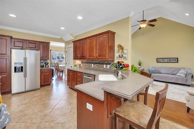 kitchen with kitchen peninsula, ornamental molding, stainless steel appliances, ceiling fan, and sink